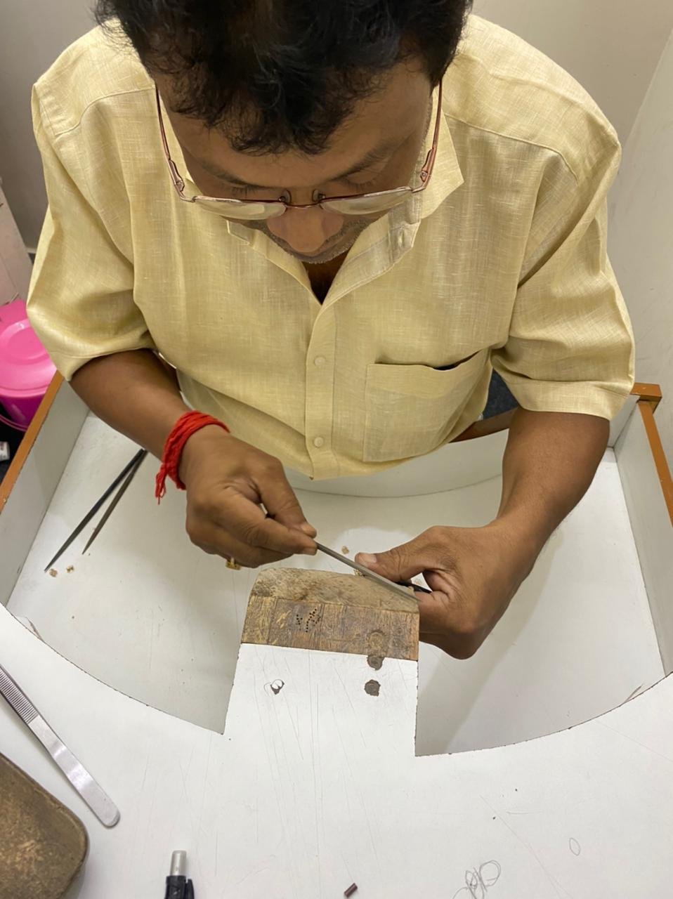 Craftsman filing a jewellery piece at the bench