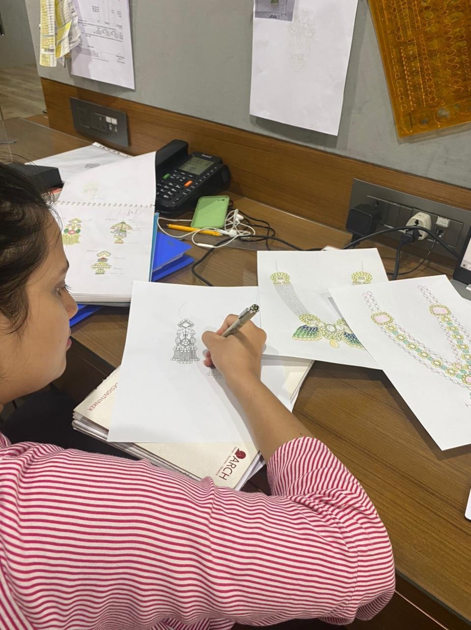 Designer refining coloured necklace sketches