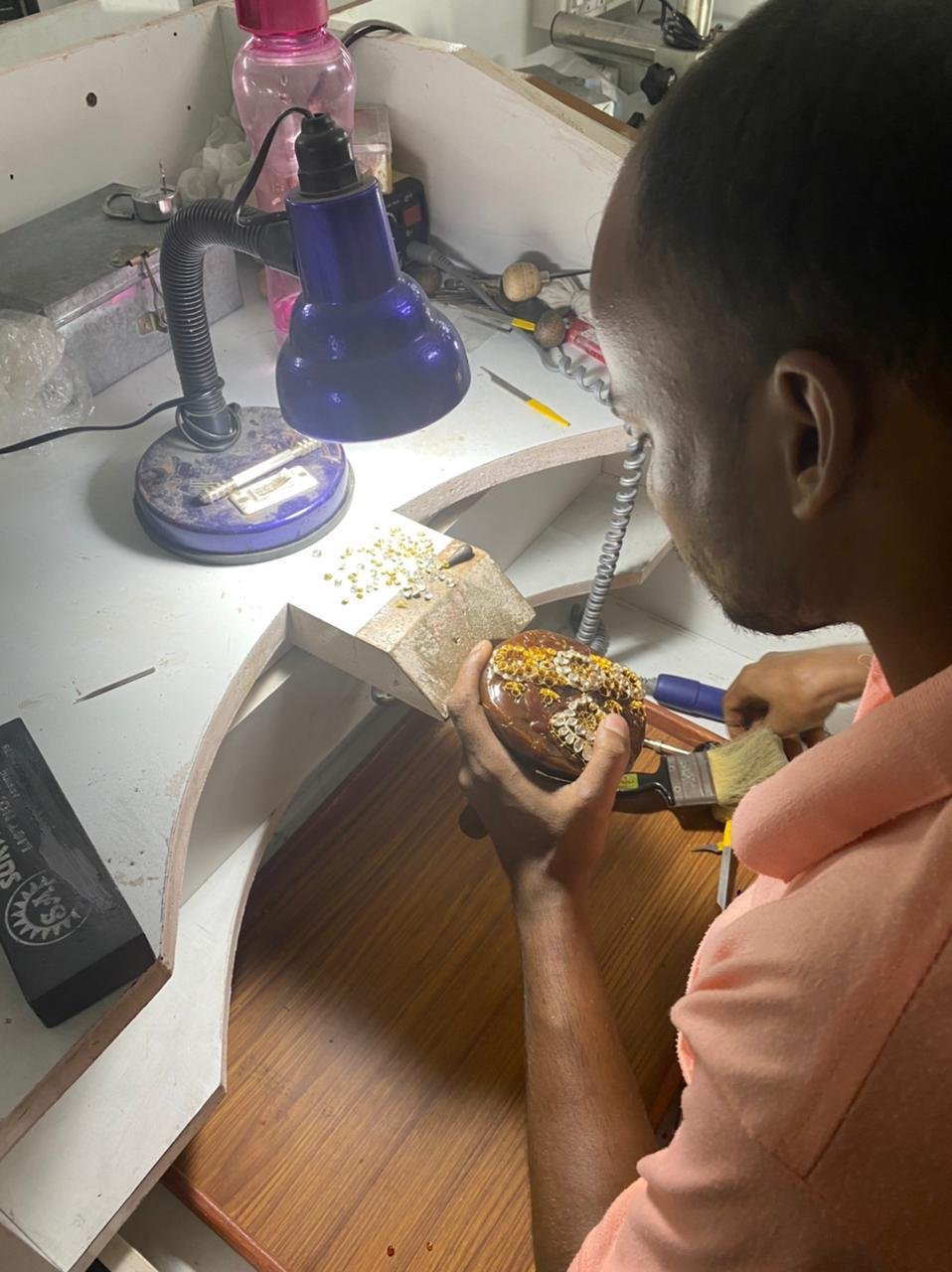 Craftsman setting stones on a mounted piece under a lamp